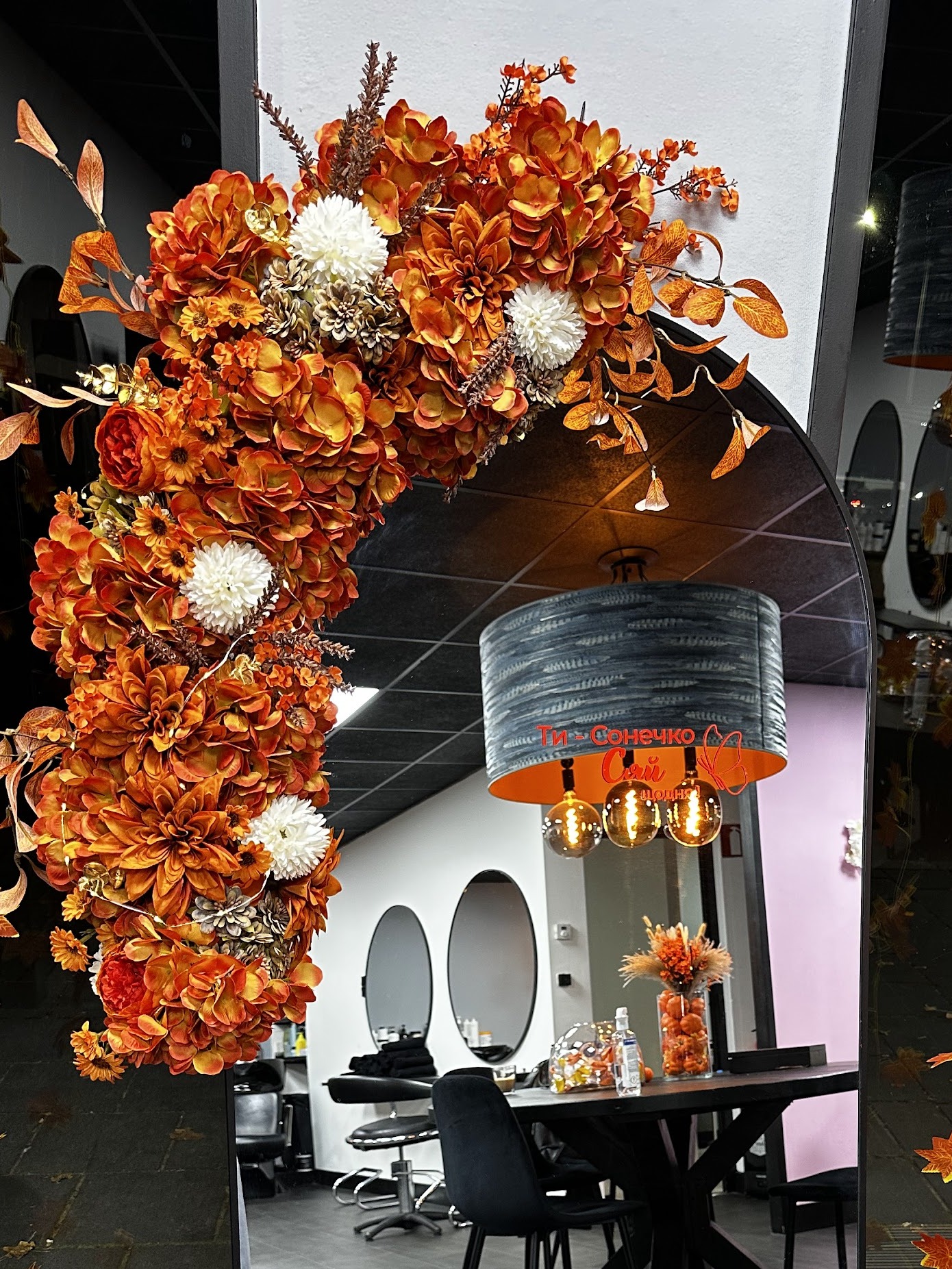 Een boog van herfstbloemen in de studio, met de spiegels en de ronde tafel erachter