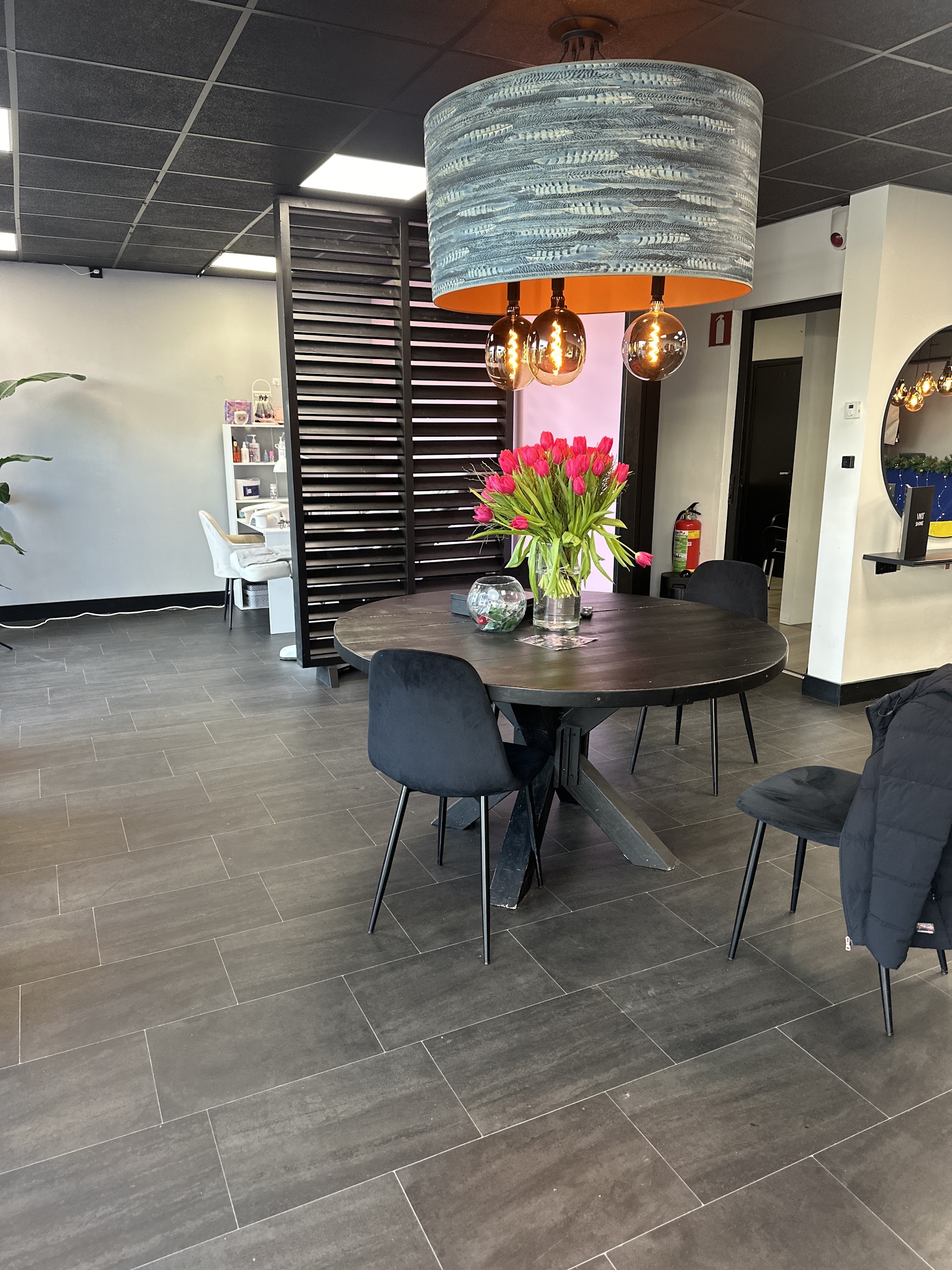 De zitruimte met een ronde donkere tafel, tulpen en een grote hanglamp
